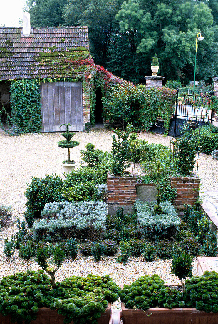 Formale Gartenanlage mit Buchsbaumhecken vor bewachsenem Gartenhaus