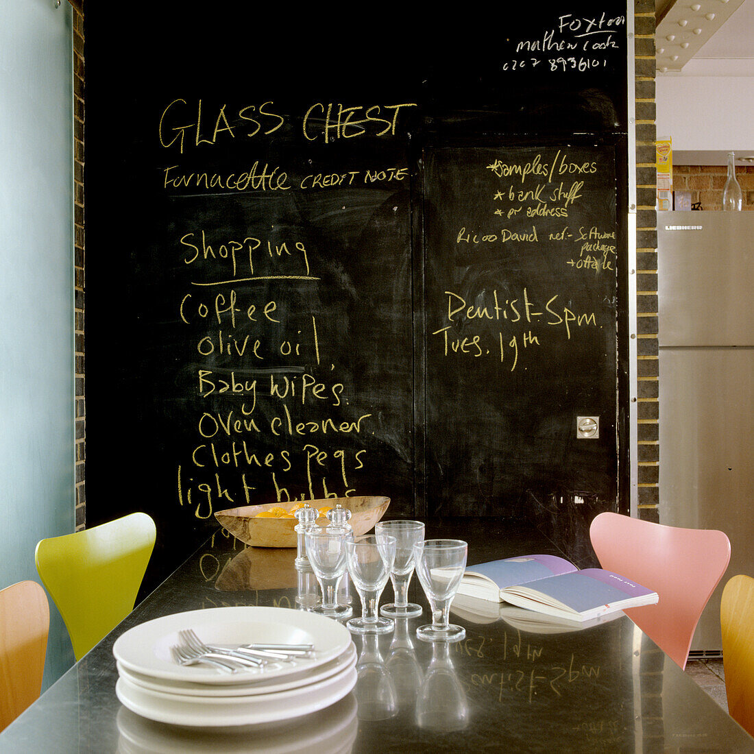 Blackboard wall with handwritten notes and colourful chairs at dining table