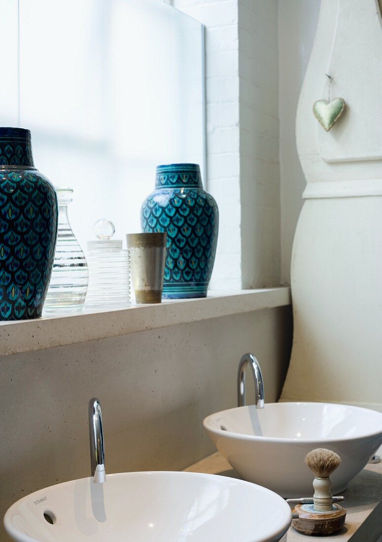 Two sinks & two blue vases on windowsill