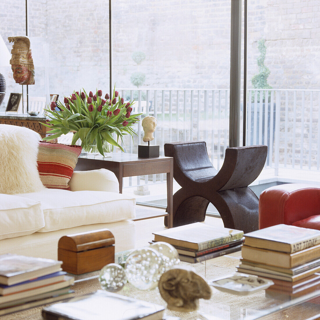 Living room with window front, white sofa and bouquet of tulips on wooden table