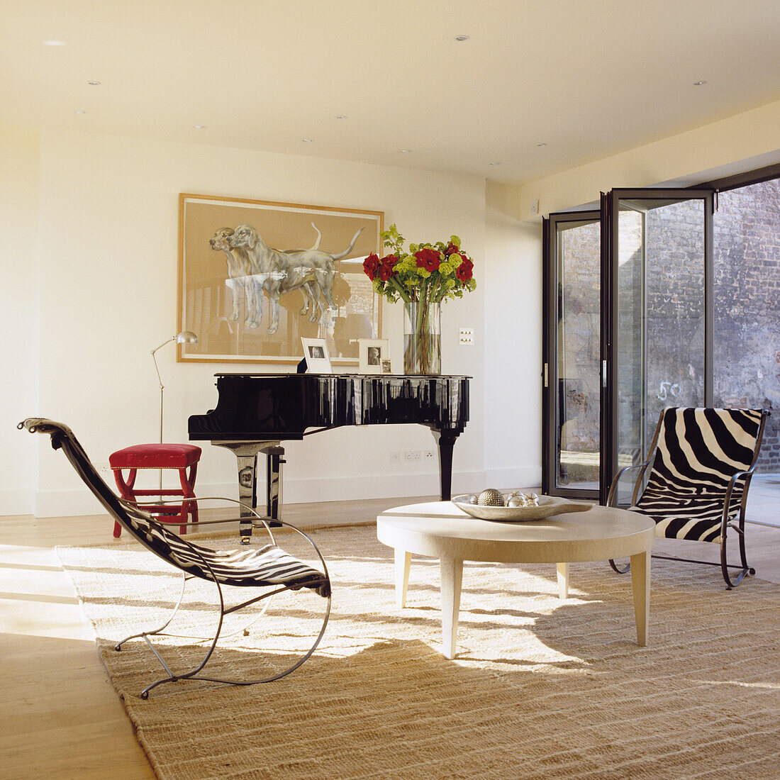 Modern living room with grand piano, armchairs with zebra pattern and floral arrangement