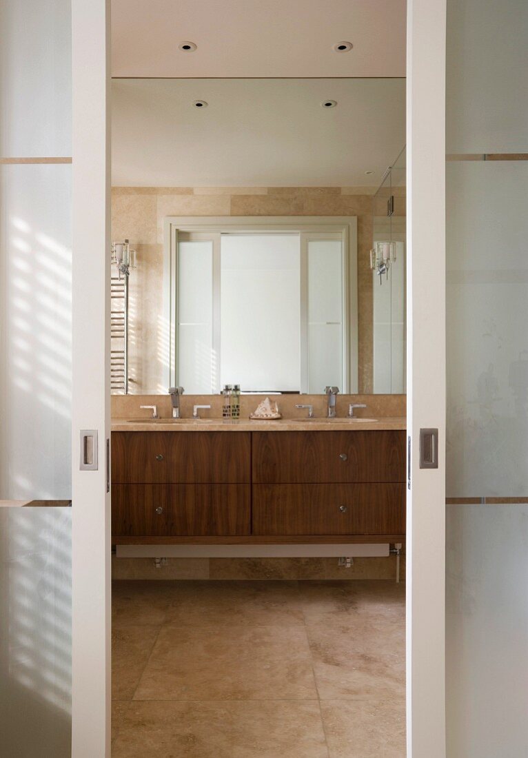 Blick in Badezimmer mit Marmorfliesen und großem Spiegel