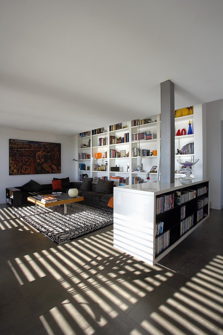 Wohnbereich im offenen Wohnraum, abgegrenzt durch ein offenes Sideboard mit Bücherregal an der Rückwand