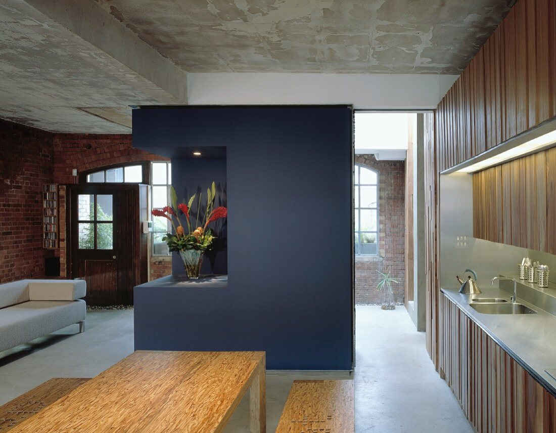 Open-plan living space in converted factory building with blue-painted partition