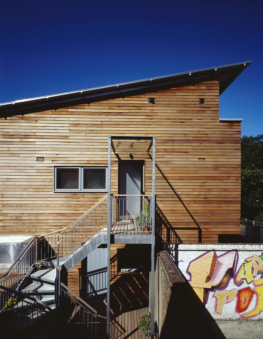 Modernes Wohnhaus mit Holzfassade und Zugang über Treppe aus Metall
