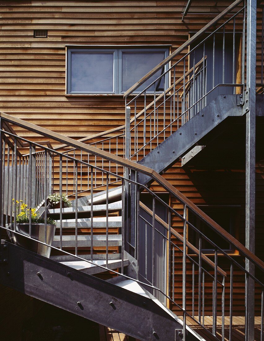 Aussentreppe aus Metall vor Holzfassade eines modernen Wohnhauses