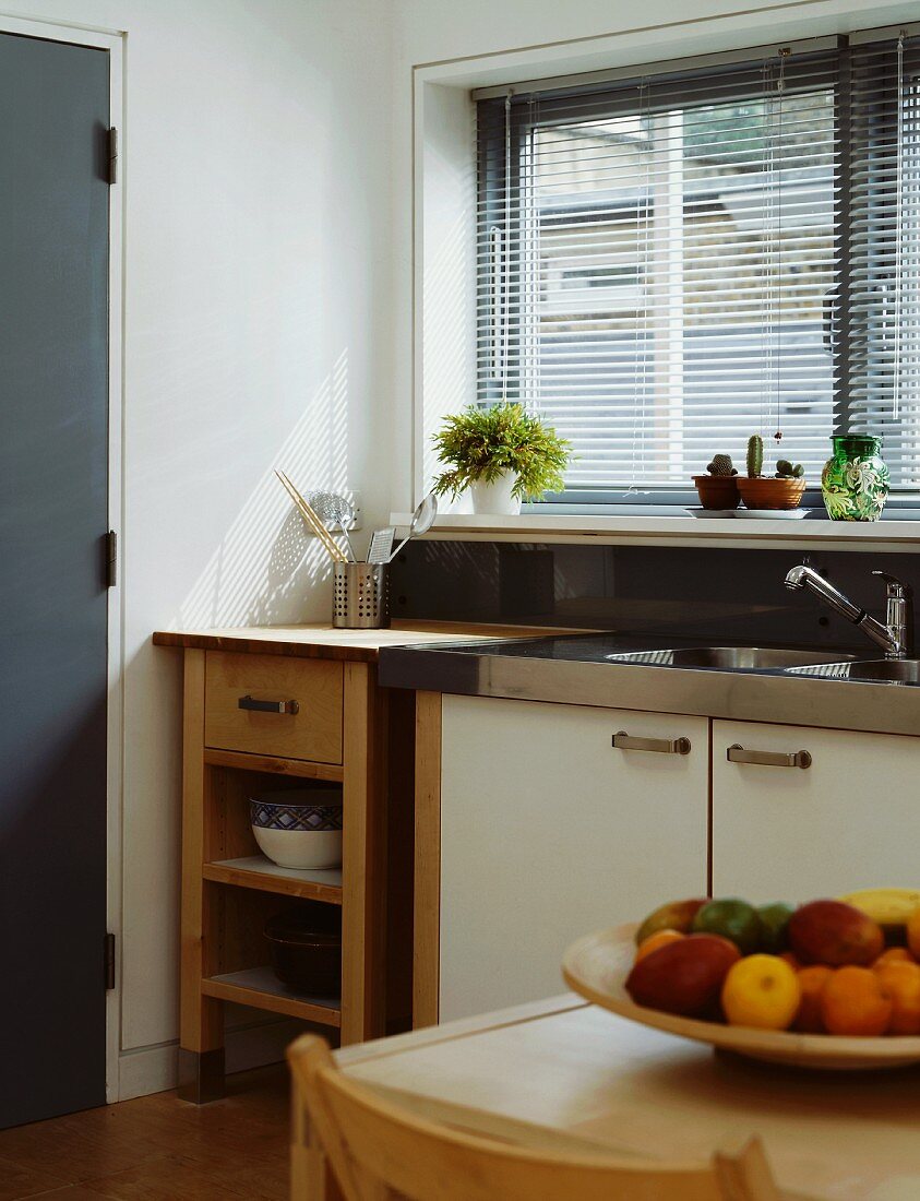 Küchenecke mit Spüle und Holzschränkchen am Fenster