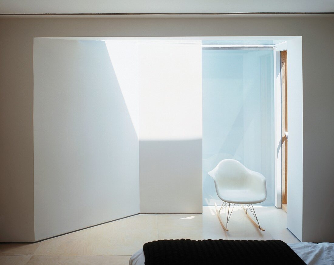 Bedroom with white shell chair in sunny anteroom leading to bathroom
