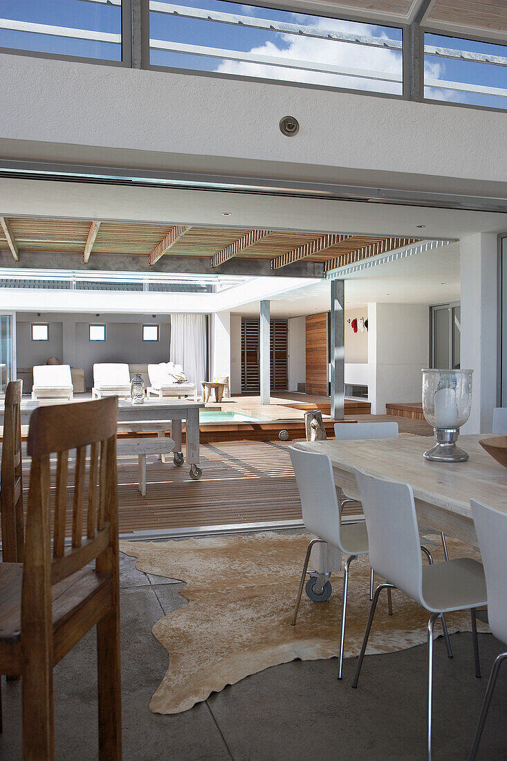 Modern dining room design with wooden table and white chairs, cowhide rug