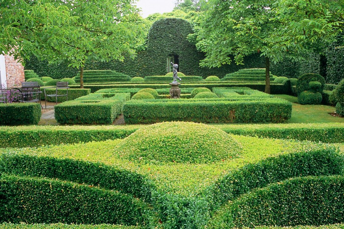 Eindrucksvolle Gartenanlage mit formgeschnittenen Hecken und gestalteten Wegen, ein Beispiel für Gartenarchitektur.