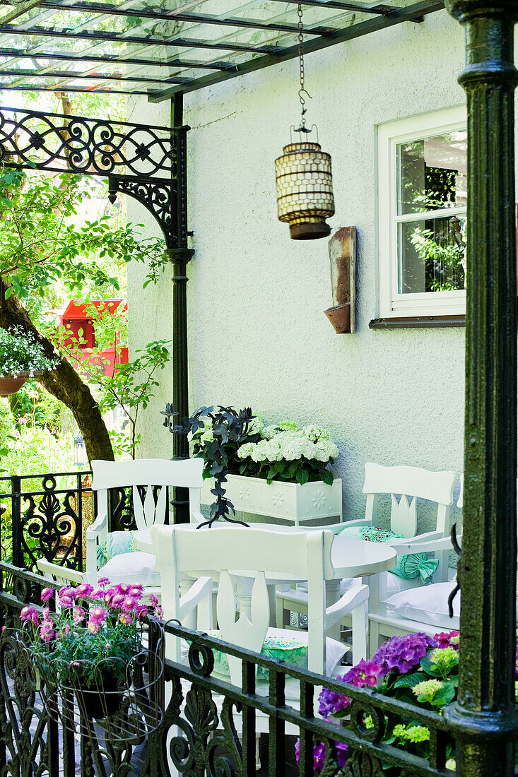 Terrasse mit weißen Möbeln und Hängelaterne im Sommer