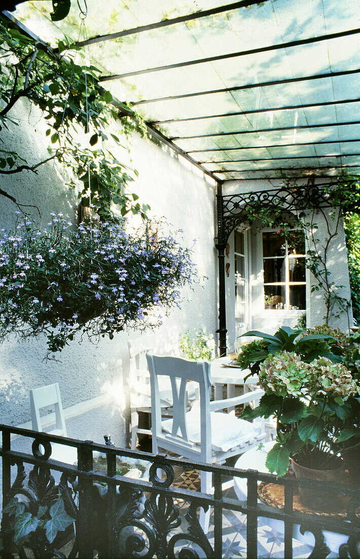 Covered patio seating area with white furniture and plants