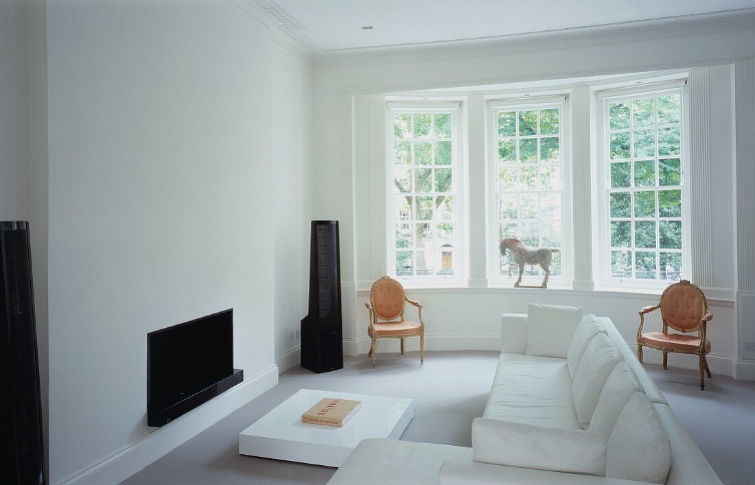 Moderne Wohnzimmergestaltung mit weißem Sofa vor Kamin im klassischen Ambiente