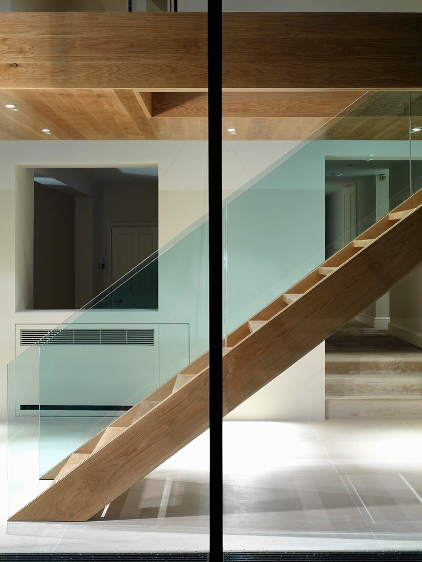 Blick durch Fenster auf Treppe aus Holz im zeitgenössischen Vorraum
