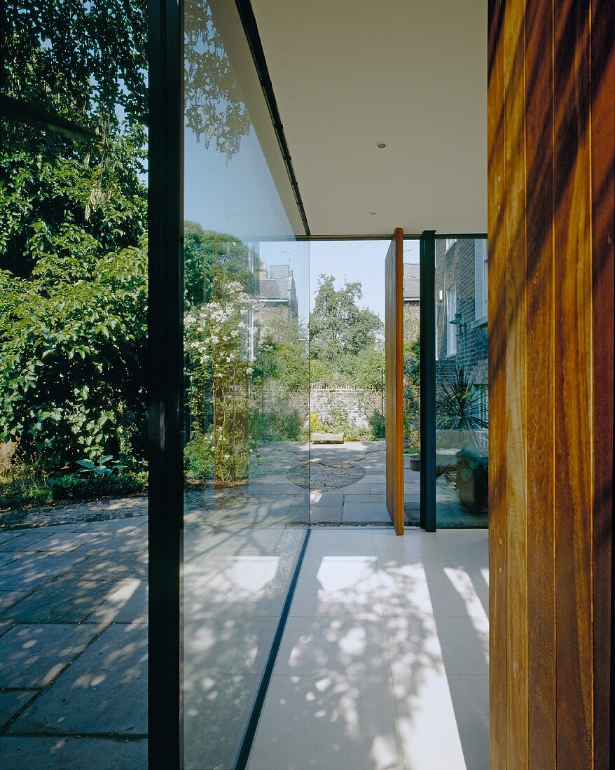 Contemporary building with glass wall and open door with view of terrace