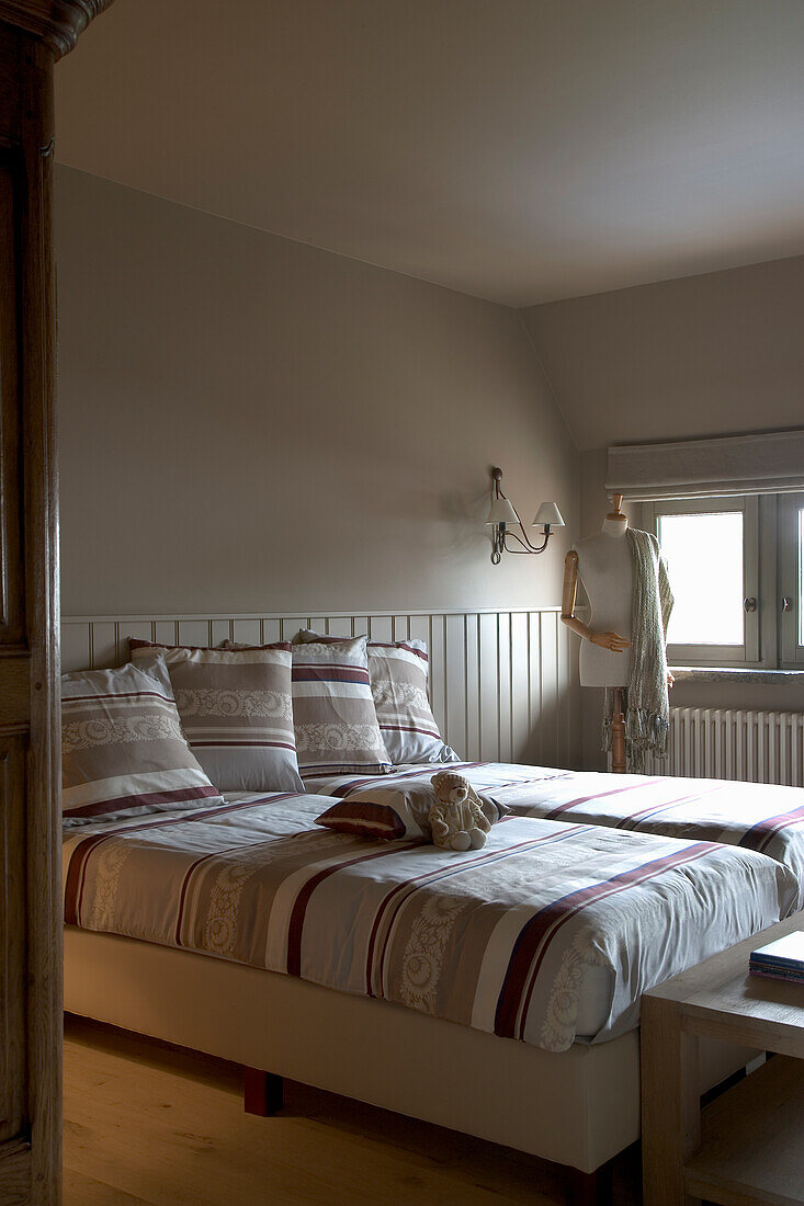 Doppelbett mit gemusterter Bettwäsche und Ankleidepuppe im Schlafzimmer