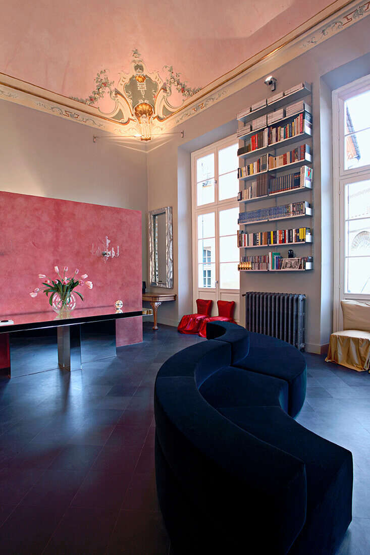 Room with stucco decoration on the ceiling, dark sofa and bookshelf