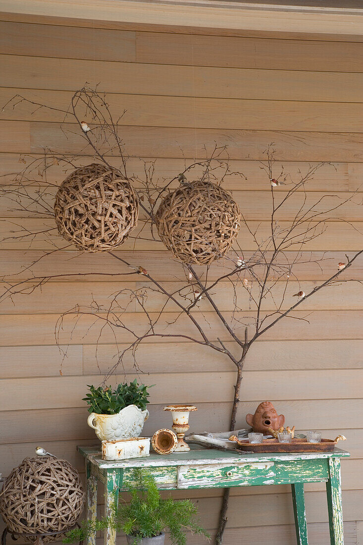 Decorative balls of twigs and vines on wooden wall with rustic side table