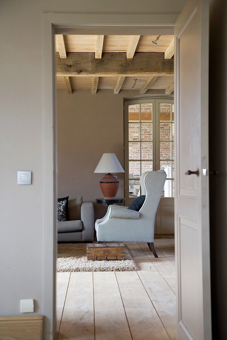 View through open door into country-house living room with wing-back chair
