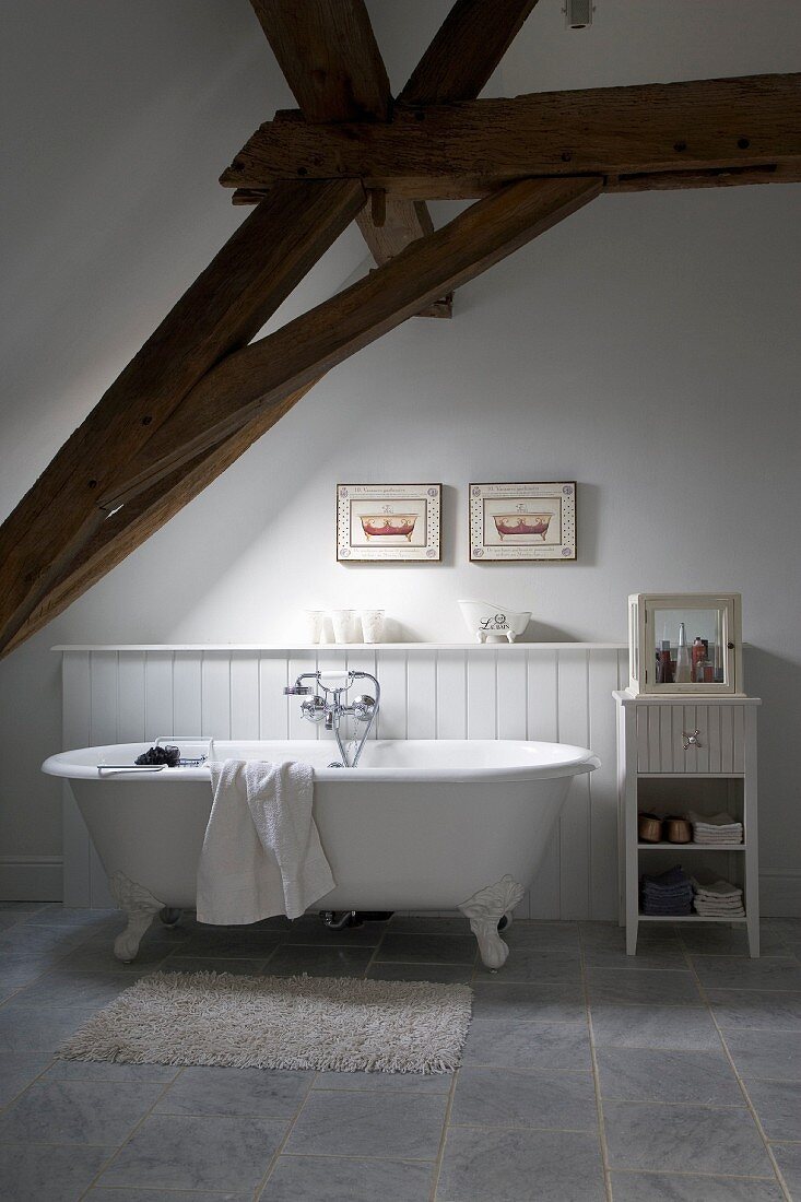 Free-standing, clawfoot bathtub under exposed roof structure