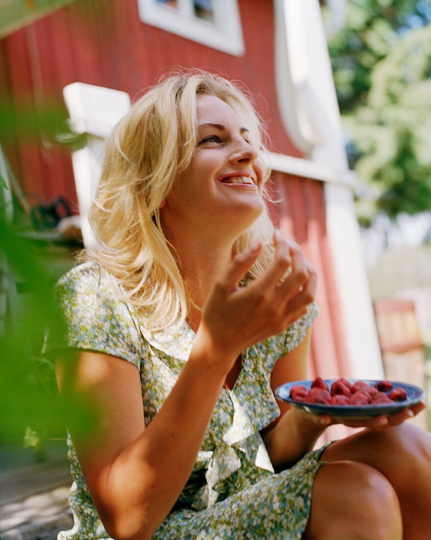 Young woman eating strawberries in garden
