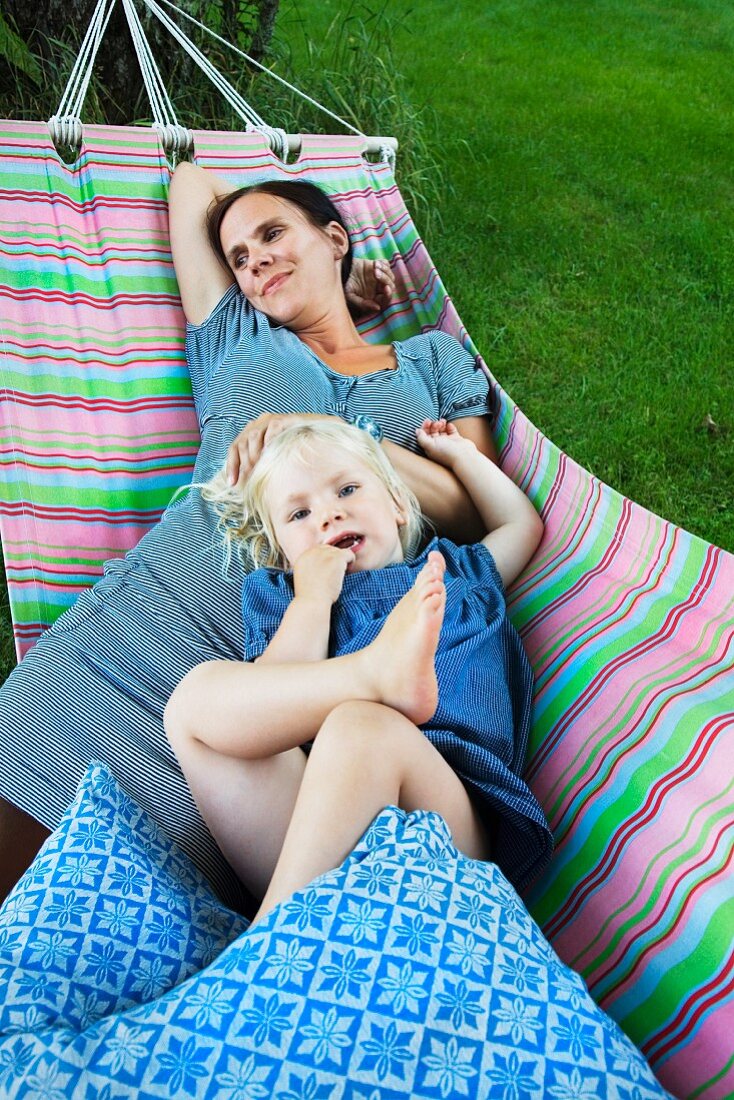 Mother and daughter lying in hammock in garden