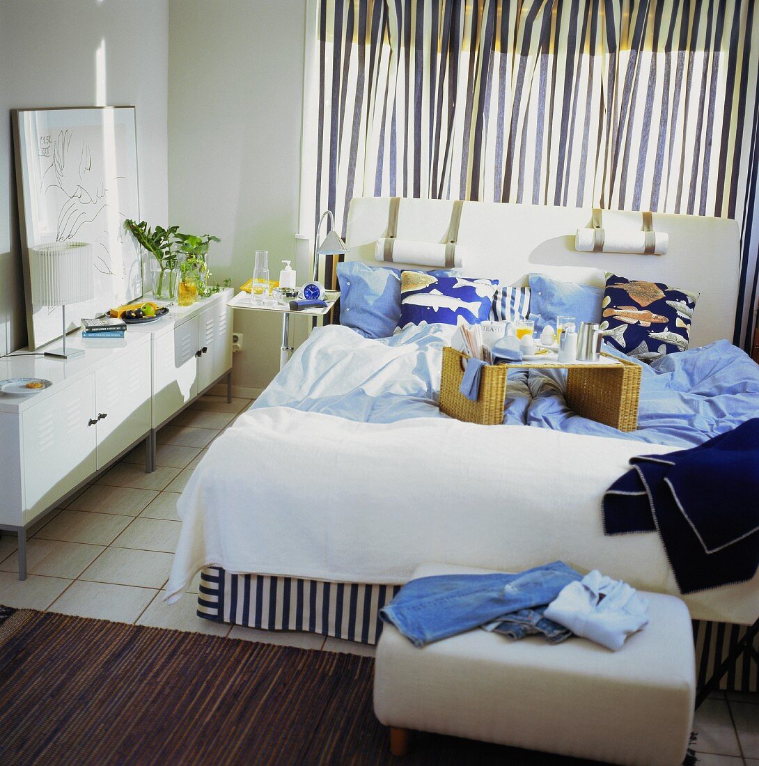 Ein Schlafzimmer mit gestreiften Vorhängen und mit Frühstückstablett auf dem Bett