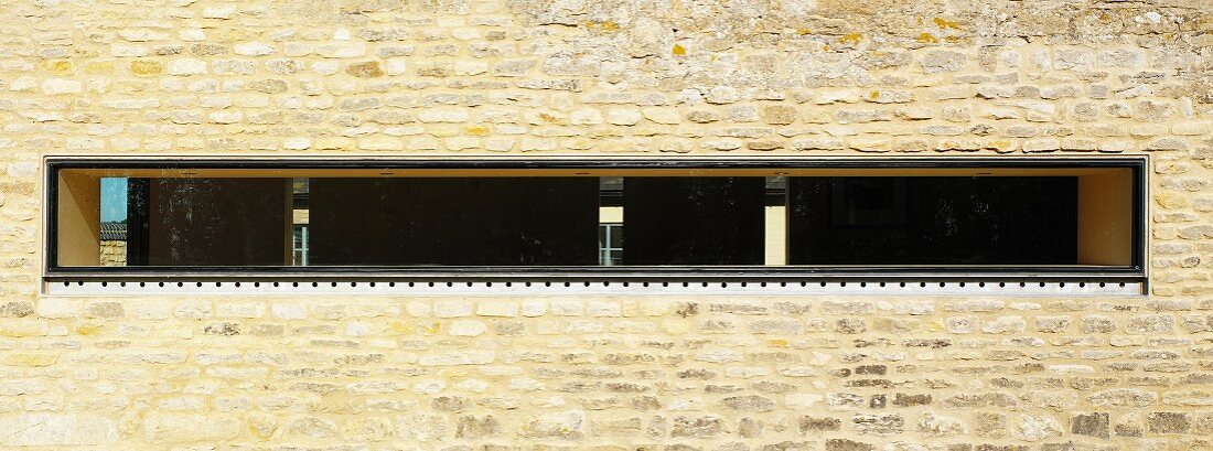 Schmaler horizontaler Fensterschlitz in Natursteinfassade