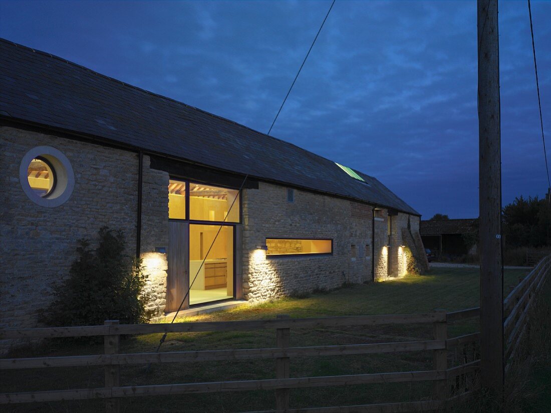 Renovated farmhouse at dusk with illuminated windows