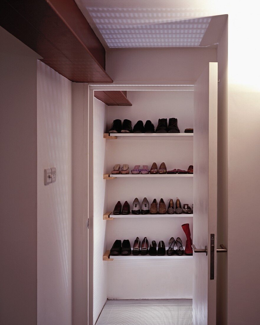 View of fitted shelving with shoes through open door