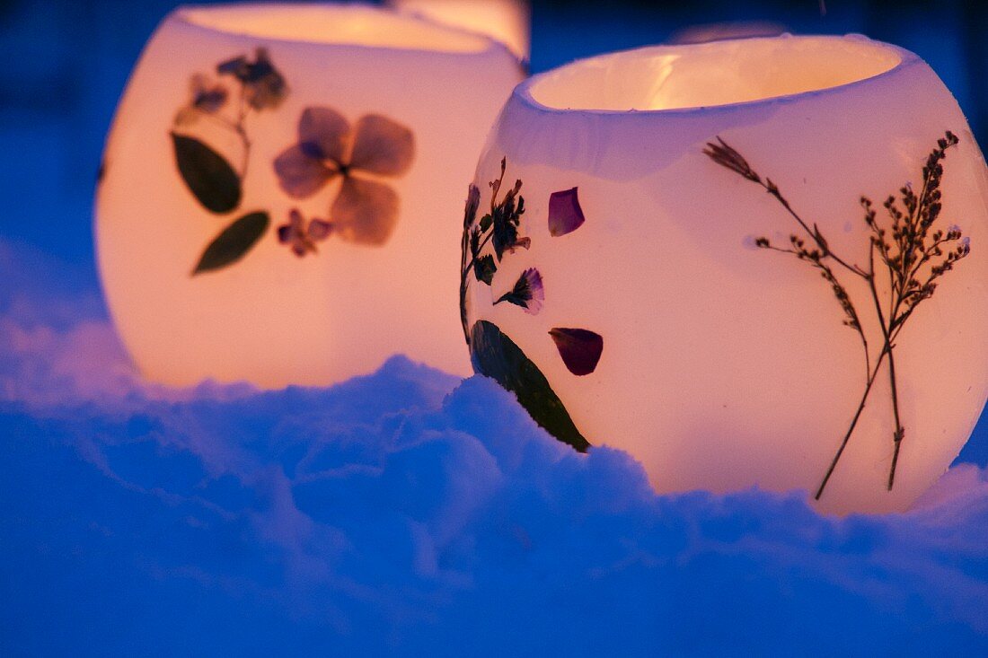 Windlichter mit gepressten Blüten im Schnee