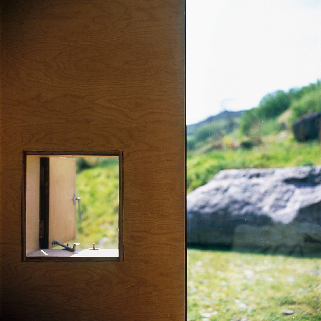 Holzwand mit Fensterausschnitt und Blick auf die Landschaft