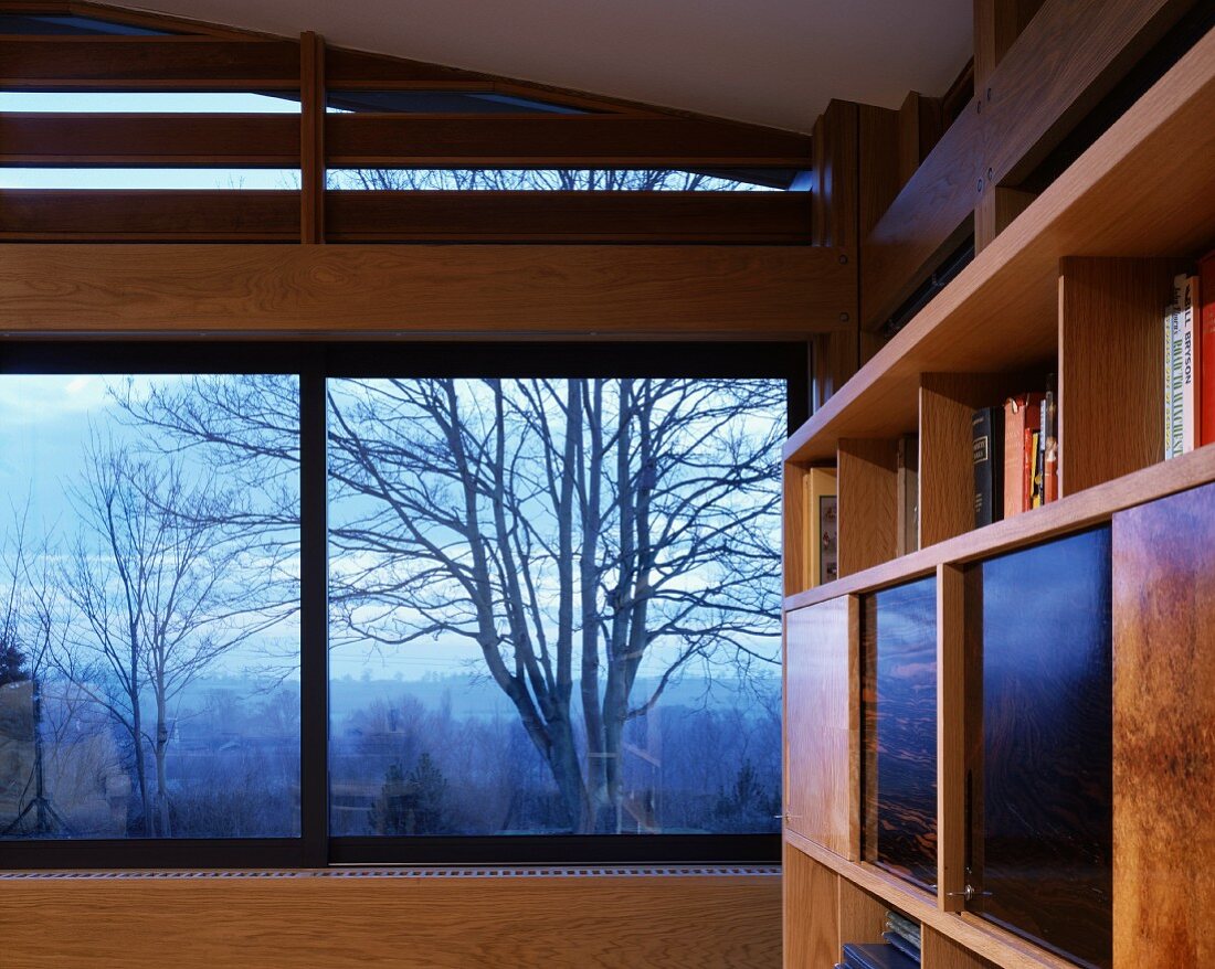 Ausschnitt eines Wohnraumes mit Panoramafenster und Blick auf herbstliche Landschaftsstimmung