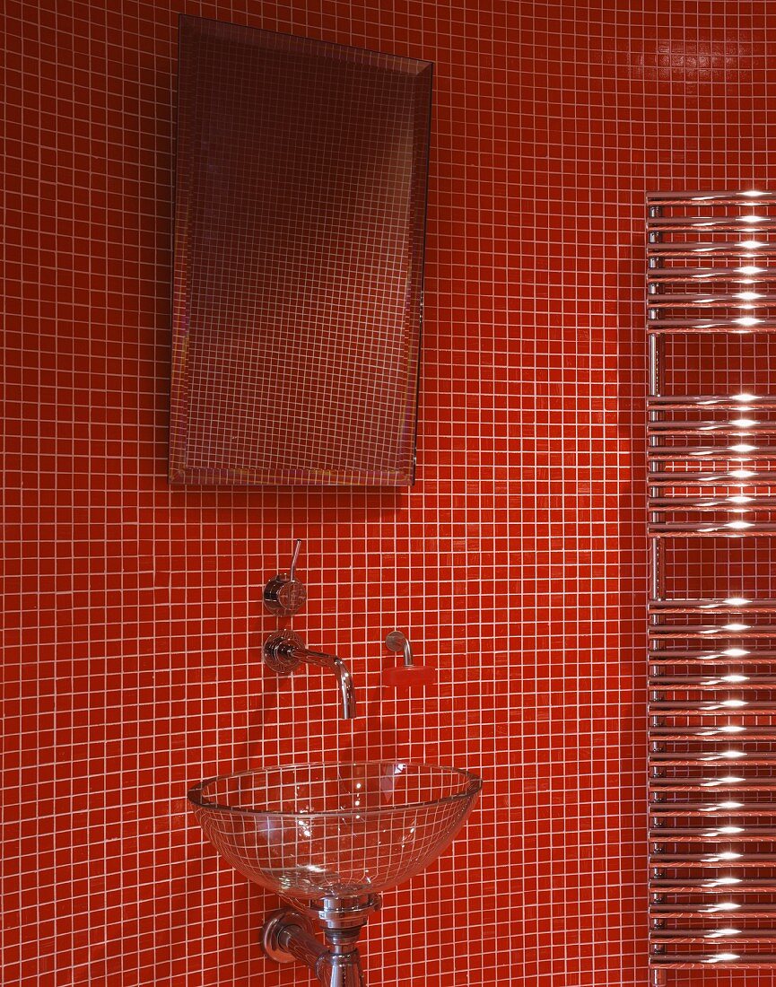 Waschschüssel aus Glas und Spiegel vor roter Mosaikfliesenwand