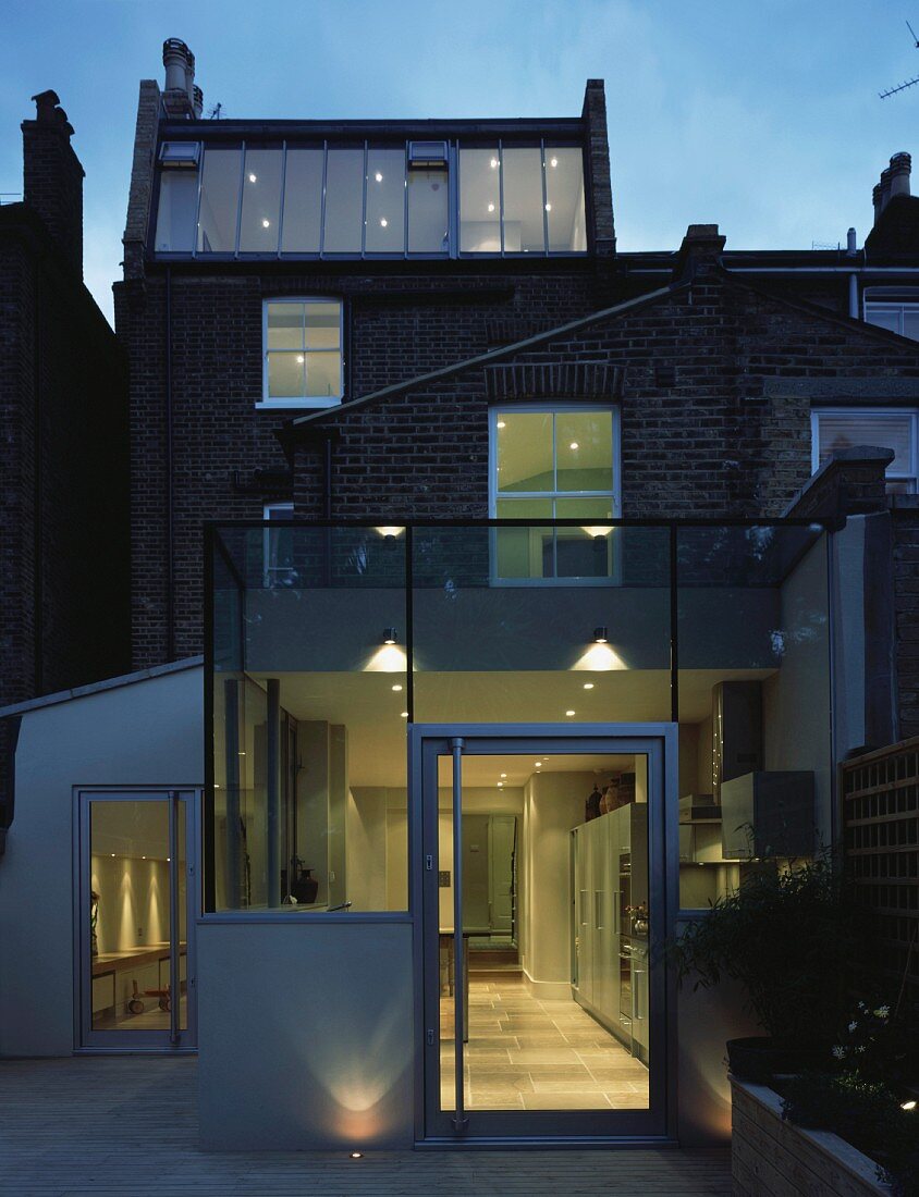 Contemporary extension on illuminated house at dusk