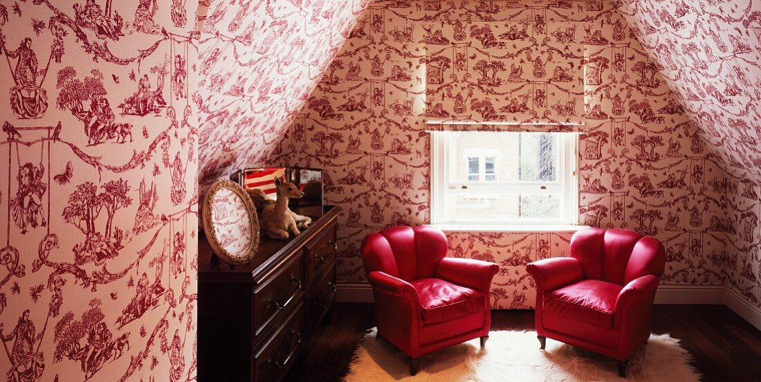 Dachzimmer mit roten Sesseln vor Wand mit erotischen Motiven auf Tapete