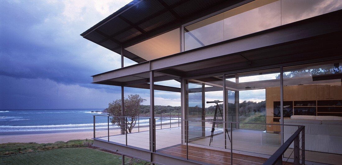 Contemporary, steel and glass house on coast with dramatic clouds