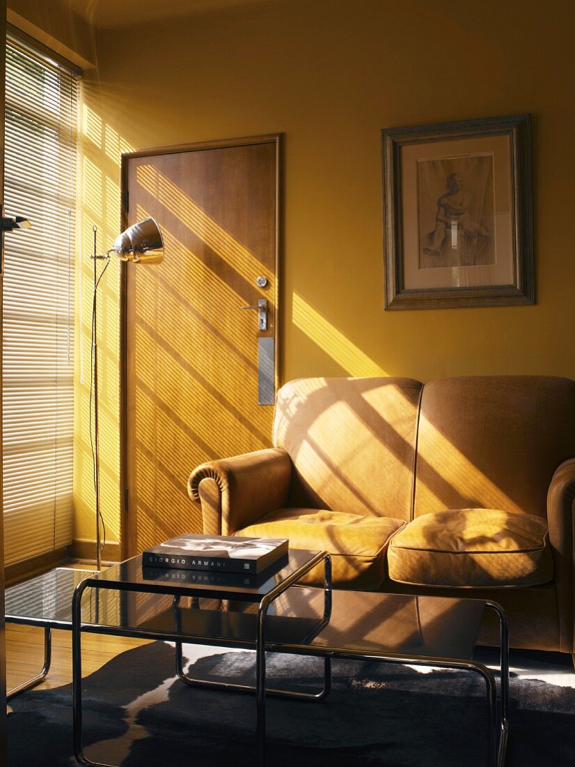 Wohnzimmer mit einem Zweisitzer vor der gelben Wand