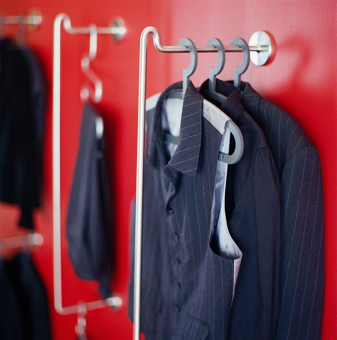 Herrenbekleidung auf Kleiderbügeln vor roter Wand