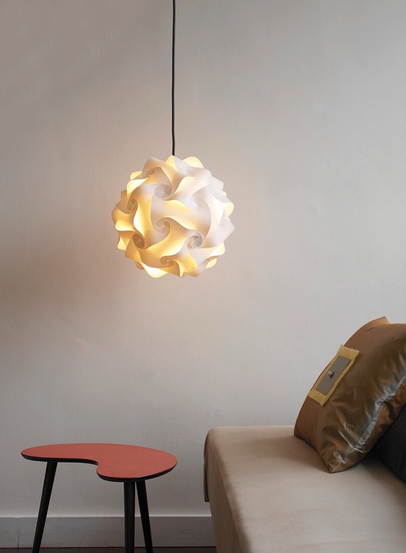 Designer-Lampe hängt über einem Hocker neben dem Sofa