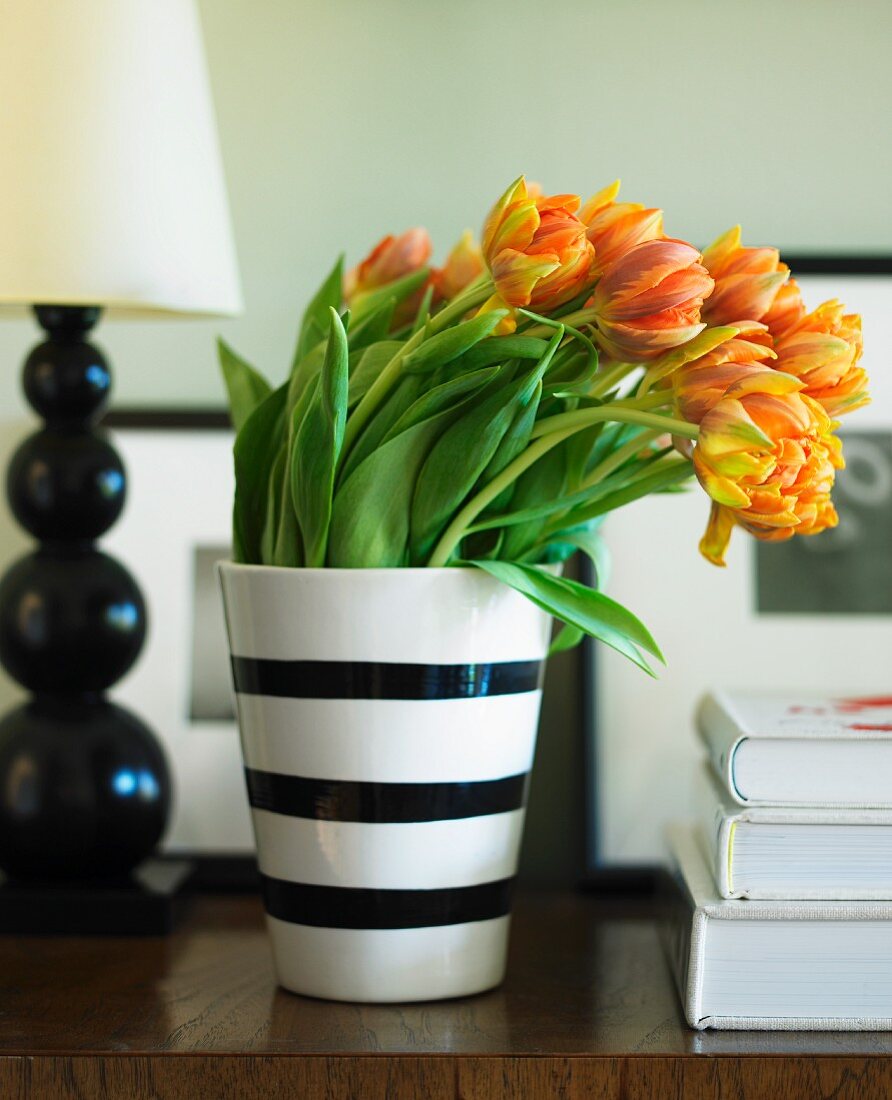 Orange Tulips in a Black and White Striped Vase on a Table
