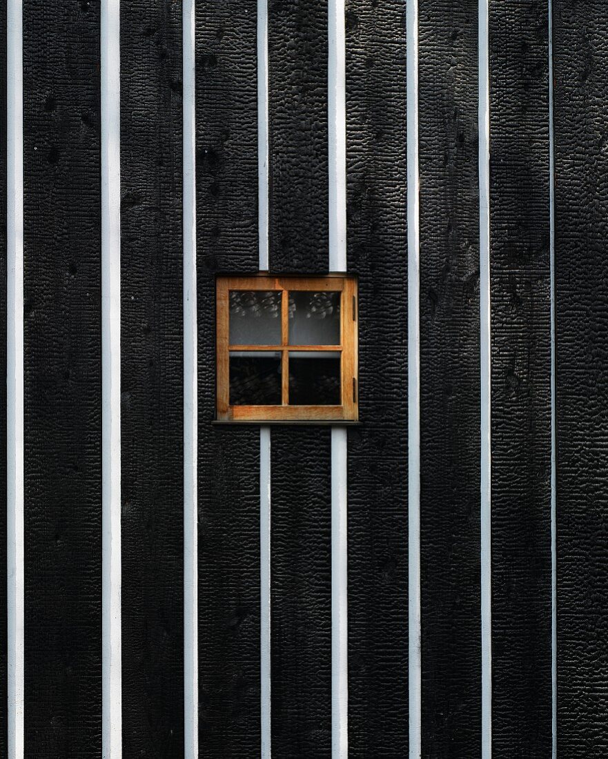 Schwarzweisse Holzwand mit kleinem Fenster