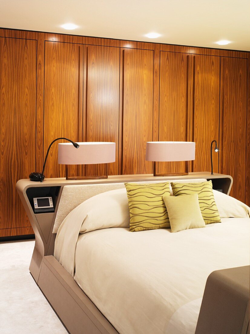 Nachttischleuchten auf Kopfteil des Doppelbetts vor Einbauschrank aus Holz