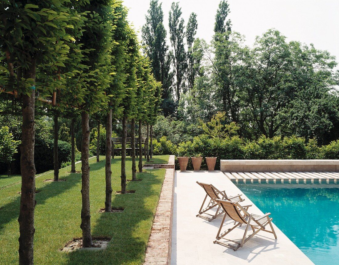 Landschaftsgarten mit Holzliegestühlen an Swimmingpool