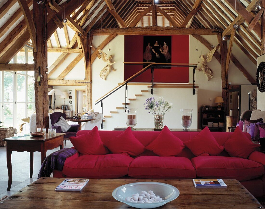 Stilmix in weiträumiger, umgenutzter Scheune - Wohnbereich mit pinkfarbenem Sofa