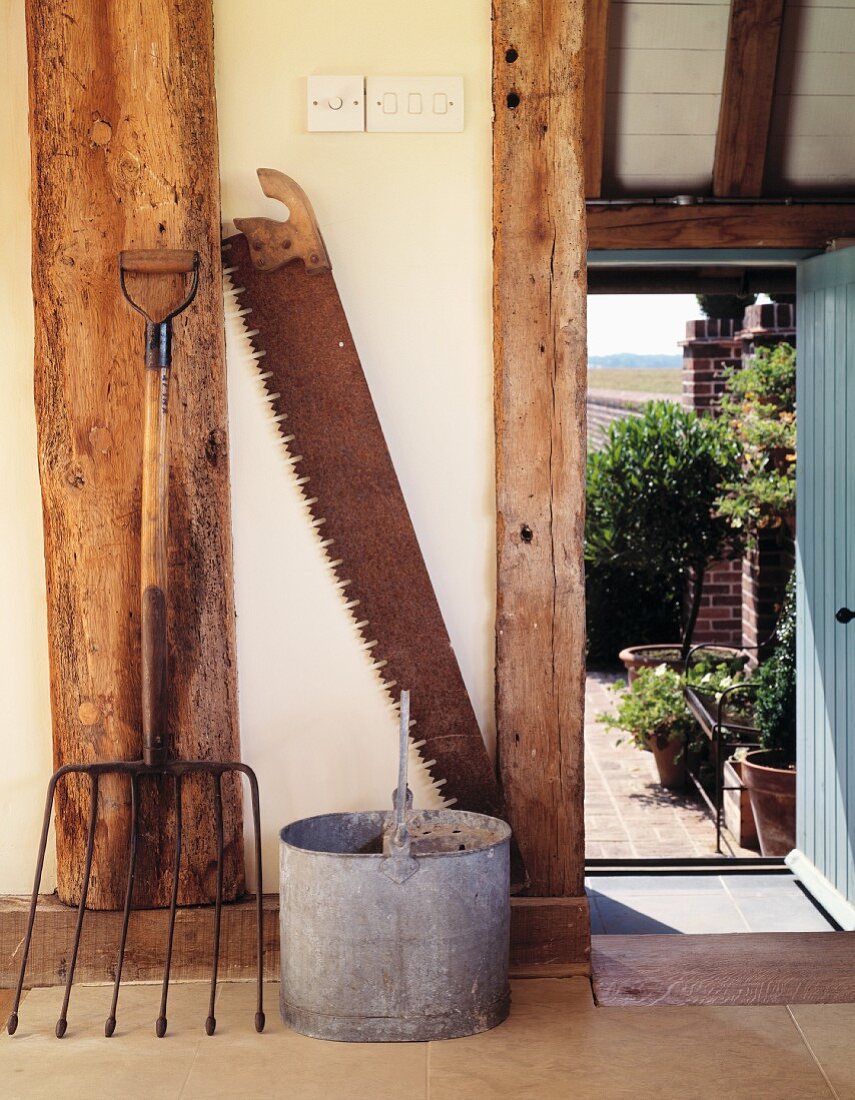 Antikes, bäuerliches Gerät vor Fachwerkbalken und offene Tür zum Garten