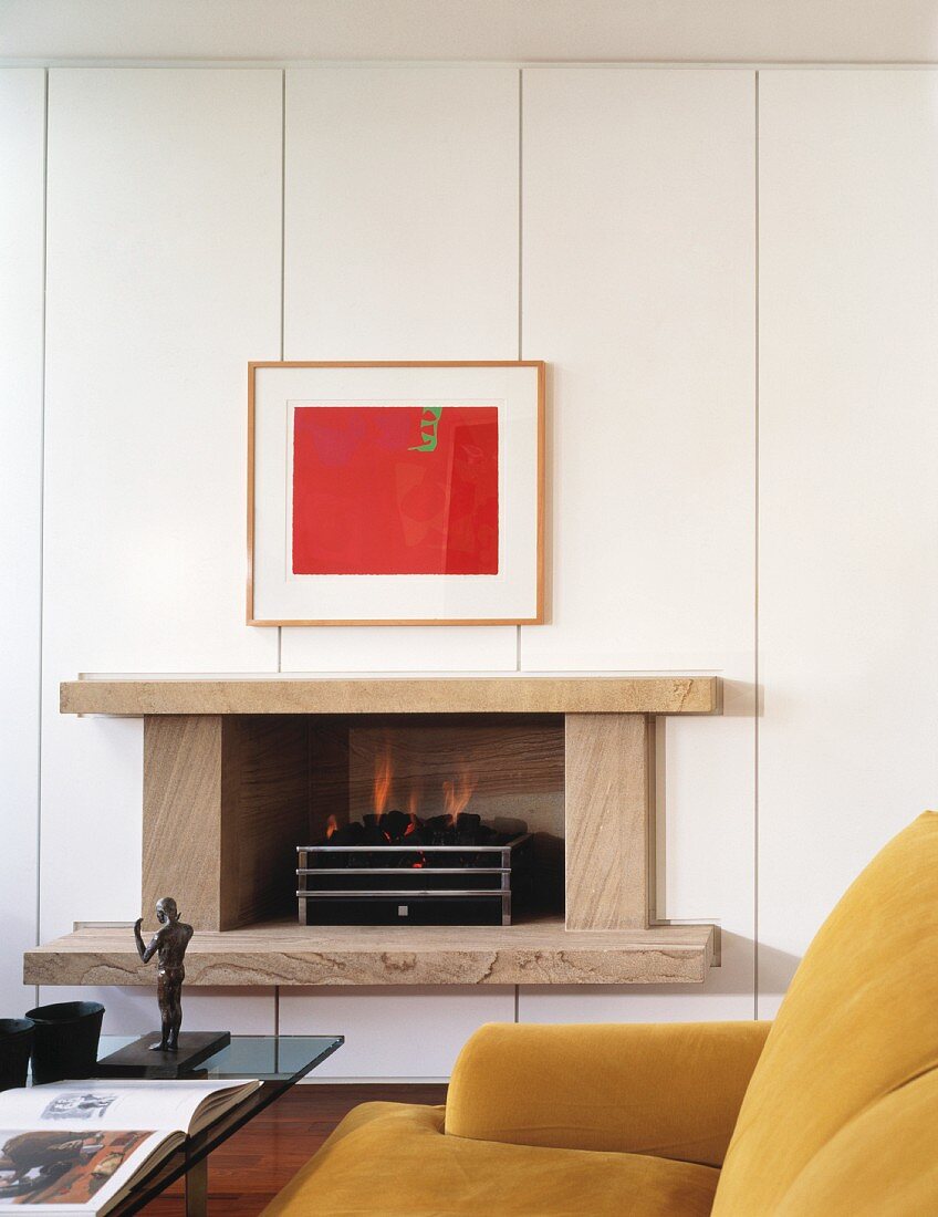 Red picture and modern fireplace with stone surround in white, panelled wall