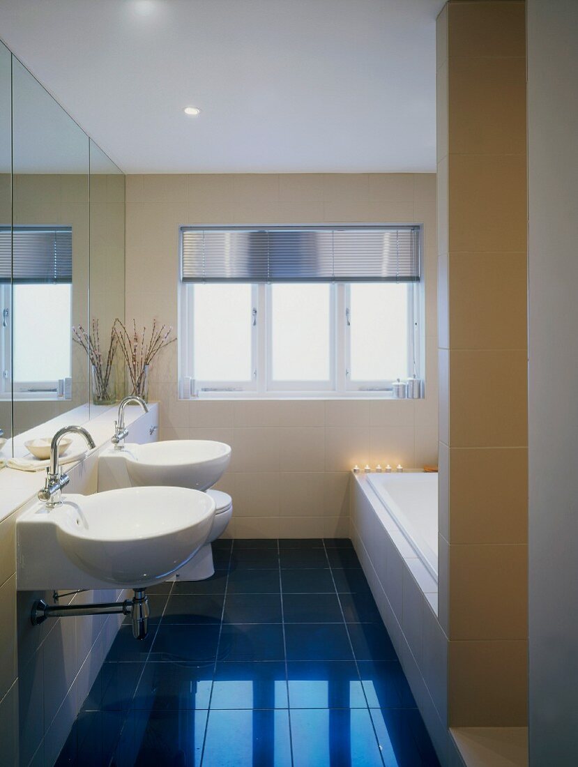 Optische Vergrösserung durch Spiegelfront in schmalem, modernem Bad mit intensiv blauem Fliesenboden
