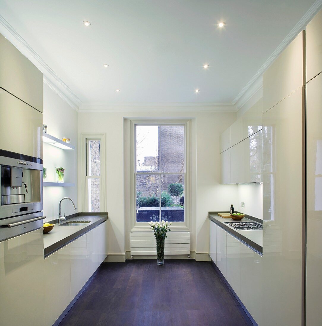 Moderne Einbauküche mit glänzenden, cremefarbenen Fronten in Londoner Altbauwohnung