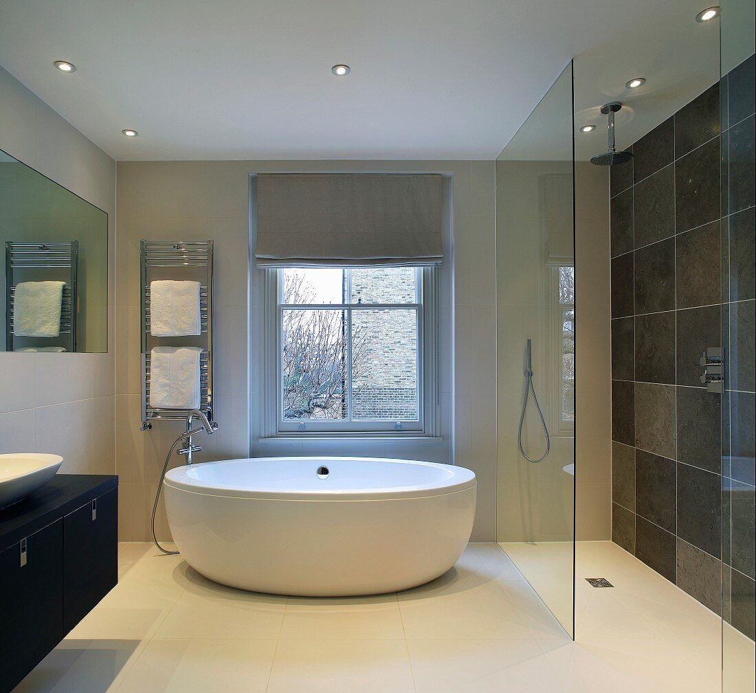 Freistehende Designer-Badewanne und bodengleiche Dusche mit Glasabtrennung im modernen Bad